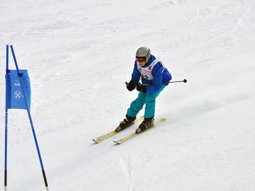 Skifahrerin in türkiser Hose auf der Rennstrecke.